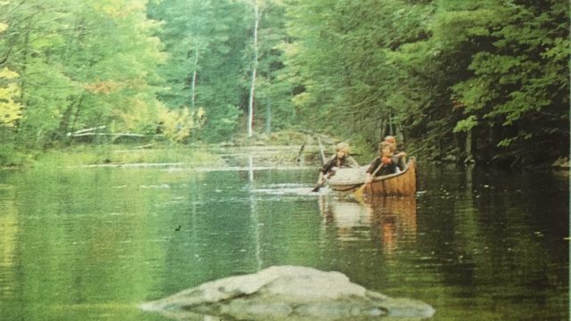 Three of the teammates row their canoe up a river.