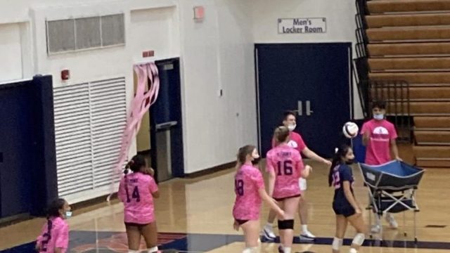 The girls volleyball team warms up for the match while wearing pink jerseys to support Breast Cancer Awareness Month.
