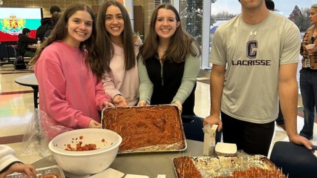 (Left to right) Italian students Liliana Lobosco, ‘27, Maria Mazzone, ‘27, Lilly Stella, ‘26, and Antonio Raimondi, ‘26, stand by their table with appetizers like bruschetta, focaccia, and pizzelle.