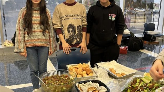 (Left to right) Turkish students Meyra Ozkanca, ‘25, Mehmet Coskun, ‘25, and Bera Uslu, ‘26, stand by their table with dishes like sarma, kısır, and çiğ köfte.